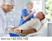 Young female doctor gives injection of botulinum toxin to man patient in forehead. Стоковое фото, фотограф Яков Филимонов / Фотобанк Лори