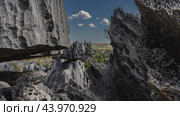 Bizarre karst rocks. Close-up. The texture. Rough grey furrowed slopes, sharp peaks against a background of blue sky, clouds and valley landscape. Madagascar. Tsingy De Bemaraha (2023 год). Стоковое фото, фотограф Вера Ивановна Кубарева / Фотобанк Лори