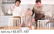 Competitive middle-aged man and woman conflicting and old woman writing inheritance sitting at kitchen table. Стоковое видео, видеограф Яков Филимонов / Фотобанк Лори