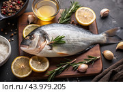Delicious and healthy fish. Raw dorado with lemon and ingredients on a dark background. Banner, menu, place for recipe text, top view. Стоковое AI-изображение, AI-художник Photojuli / Фотобанк Лори