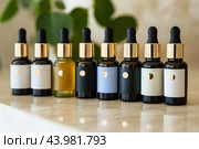 A collection of various essential oil bottles arranged elegantly on a marble surface in a bright indoor setting. Стоковое AI-изображение, AI-художник Сергей Толмачёв / Фотобанк Лори