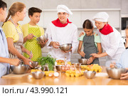 During cooking lesson, male cook tells children about culinary rules, woman assistant helps child. Стоковое фото, фотограф Яков Филимонов / Фотобанк Лори