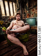 Fat man eating a hamburger sitting on a chair in the slums. Стоковое фото, фотограф Андрей Армягов / Фотобанк Лори