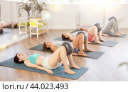 Together with students, she lies on mat, holds fitball between knees and raises and lowers buttocks. Стоковое фото, фотограф Яков Филимонов / Фотобанк Лори