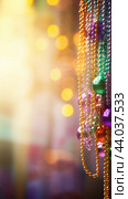 Colorful Mardi Gras beads and bokeh lights festive background. Стоковое AI-изображение, AI-художник Анастасия Золотницкая / Фотобанк Лори