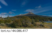 Autumn. Yellowed grass in a meadow, on the shore of a lake. The forest grows towards the foot of the mountain. A snow-capped peak against a blue sky and clouds. Argentina. Patagonia. Lapataia Bay. Стоковое фото, фотограф Вера Ивановна Кубарева / Фотобанк Лори