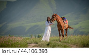 Asian girl (Kyrgyz) in a white dress walks with a horse in nature against the backdrop of mountains, Bishkek Kyrgyzstan (2021 год). Стоковое фото, фотограф Evgenii Predibailo / Фотобанк Лори