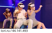 Cheerful young female friends wearing VR headsets and holding controllers having fun in virtual reality studio, competing in two-on-two shooter game. Стоковое видео, видеограф Яков Филимонов / Фотобанк Лори