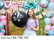 Девочка-подросток, старшая сестра держит черный воздушный шар с надписью "мальчик или девочка" на вечеринке по поводу раскрытия пола "гендер пати" в парке на улице. Вечеринка, где будет известно "брат или сестра", "он или она". Стоковое фото, фотограф Яна Проничева / Фотобанк Лори