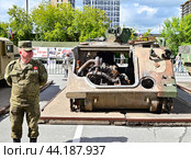 Российский военнослужащий возле разбитого американского бронетранспортера M113 A2. Выставка трофейной техники из зоны СВО. Город Тюмень (2024 год). Редакционное фото, фотограф Александр Тараканов / Фотобанк Лори