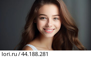 Portrait of a smiling cheerful teenage girl with perfect skin, gray background, banner. Стоковое AI-изображение, AI-художник ALLA YURTAYEVA / Фотобанк Лори