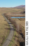 Vertical drone video of flying over a hilly rural landscape with a winding road and fish ponds. Altai Krai. Стоковое видео, видеограф Сергей Пристяжнюк (Serg Zastavkin) / Фотобанк Лори