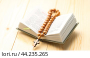 Christian books. A cross is hanging down. The cross is wooden. The book is open on a prayer page. The concept of spirituality and reverence. The concept of the Christian Faith. Стоковое фото, фотограф Скрипачев Антон / Фотобанк Лори