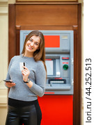 Young happy brunette woman withdrawing money from credit card at ATM. Стоковое фото, фотограф Андрей Аркуша / Фотобанк Лори