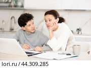 Mother helps her teenage son do schoolwork, solve problems together and find answers. Стоковое фото, фотограф Яков Филимонов / Фотобанк Лори