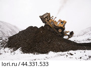 Бульдозер в горной местности сгребает кучу горного золотосодержащего грунта , который в дальнейшем будет перевозиться на промывку с целью извлечения желтого драгоценного метала. Стоковое фото, фотограф Павел Просянов / Фотобанк Лори