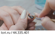 Applying a three-dimensional pattern with rhinestones and broths on the nail. Стоковое видео, видеограф Константин Мерцалов / Фотобанк Лори