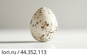A speckled egg resting on a clean white surface showcases natural beauty in a minimalist setting during bright daylight. Стоковое AI-изображение, AI-художник Сергей Толмачёв / Фотобанк Лори