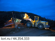 Фронтальный колесный погрузчик Komatsu WA 600 высыпает на промывку горный золотосодержащий грунт, в бункер промывочной машины. Республика САХА, ЯКУТИЯ, Оймяконский район. (2009 год). Редакционное фото, фотограф Павел Просянов / Фотобанк Лори