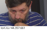 A bearded man is working at a laptop holding his chin with his hand. Стоковое видео, видеограф Ярославский Максим / Фотобанк Лори