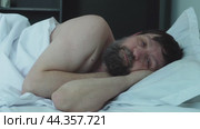 A sleeping man reluctantly wakes up in bed. Стоковое видео, видеограф Ярославский Максим / Фотобанк Лори