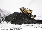 Бульдозер в горной местности сгребает кучу горного золотосодержащего грунта , который в дальнейшем будет перевозиться на промывку с целью извлечения желтого драгоценного метала. Стоковое фото, фотограф Павел Просянов / Фотобанк Лори