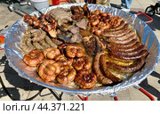 Огромная сковорода, на которой жарятся мясные колбаски из разных сортов мяса на гастрономическом фестивале в Парке 300-летия Санкт-Петербурга (2024 год). Стоковое фото, фотограф Елена Яворская / Фотобанк Лори
