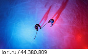 Two hockey players in action under colorful lighting on the ice rink during a competitive match at night. Стоковое AI-изображение, AI-художник Сергей Толмачёв / Фотобанк Лори