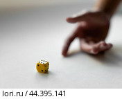 Hand in motion with yellow dice on a white surface capturing chance and luck. Стоковое фото, фотограф Lamina Akulova / Фотобанк Лори