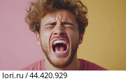 Young man screaming with eyes closed on pink and yellow background. Стоковое AI-видео, аниматор Юрий Поздников / Фотобанк Лори