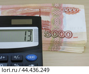 Налог на доходы физических лиц. Ставка тринадцать процентов на табло калькулятора и пачка пятитысячных купюр. Стоковое фото, фотограф Татьяна Т / Фотобанк Лори