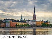 Old Town Waterfront. Gamla Stan, Stockholm, Sweden. Riddarholmen church with spire and colorful historical buildings. (2019 год). Стоковое фото, фотограф KOSIM / Фотобанк Лори