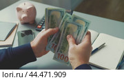 Counting cash while budgeting at a desk with savings tools and a calculator. Стоковое видео, видеограф Сергей Толмачёв / Фотобанк Лори