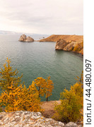 Baikal Lake on October. View of famous Shamanka Rock - natural landmark of Olkhon Island. Scenic autumn landscape with yellowed larch trees. Natural seasonal background. Travel and outdoor recreation. Стоковое фото, фотограф Виктория Катьянова / Фотобанк Лори