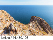 Lake Baikal on sunny autumn day. Typical view of lake with steep cliffs covered with red lichens and mosses and endless expanse of blue water of lake. Travels in Tazheran steppe and coast of Baikal lake. Стоковое фото, фотограф Виктория Катьянова / Фотобанк Лори