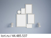 The image features a blue wall with five white picture frames and two white sconces. Concept of interior design mockup. Стоковое фото, фотограф Ольга Петрова-Апостолова / Фотобанк Лори