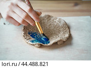 Unrecognised Woman making pattern on ceramic plate, hands close-up. Стоковое фото, фотограф Natalia Gdovskaia / Фотобанк Лори