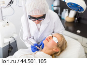 Focused cosmetologist performing laser resurfacing to young woman. Стоковое фото, фотограф Яков Филимонов / Фотобанк Лори