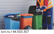 Waste management worker sorts recyclable materials in a busy urban area during daylight hours. Стоковое видео, видеограф Сергей Толмачёв / Фотобанк Лори