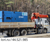 Industrial generator branded "SDMO" and "MSK energo" mounted on a white cargo truck with a red crane, parked on a roadside near a forest - Moscow, Russia, March 20, 2023. Редакционное фото, фотограф Андрей Журавлев / Фотобанк Лори