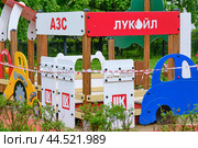 Children's playground with a Lukoil-themed gas station and play structures. Colorful equipment with wooden elements and toy gas pumps. Outdoor activity and play - Moscow, Russia, March 20, 2021. Редакционное фото, фотограф Андрей Журавлев / Фотобанк Лори