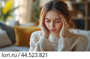 Young woman suffering from a strong headache at home. Стоковое AI-изображение, AI-художник Юрий Поздников / Фотобанк Лори