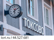 Фрагмент здания железнодорожного вокзала в посёлке Токсово. Часы и название станции. Всеволожский район Ленинградской области (2024 год). Редакционное фото, фотограф Румянцева Наталия / Фотобанк Лори