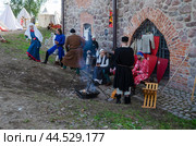 Реконструкторы отдыхают в лагере у стены средневекового замка. Фрагмент исторического фестиваля "Дни средневековья в Выборге-2024" Редакционное фото, фотограф Дмитрий Мельников / Фотобанк Лори