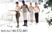 Men and women stand in second position near ballet barre during group training in a dance studio. Стоковое видео, видеограф Яков Филимонов / Фотобанк Лори
