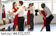 Elegant couple, smiling young guy and stylish woman in red dress enjoying slow foxtrot in dance studio. Amateur ballroom dancing concept. Стоковое видео, видеограф Яков Филимонов / Фотобанк Лори