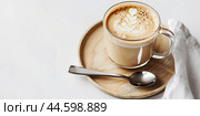 Cafe latte macchiato layered coffee in a see through coffee cup. Wooden tray with milk coffee in a transparent trendy glass mug, spoon on a white desk. Hot cappuccino coffee on table. Space for text. Стоковое AI-изображение, AI-художник Марина Демидюк / Фотобанк Лори
