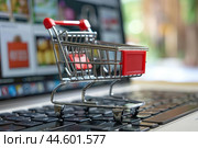 Mini shopping cart on laptop keyboard. Стоковое AI-изображение, AI-художник Иван Рябоконь / Фотобанк Лори