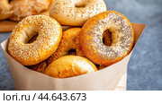A bag of assorted sesame seeded bagels in a paper basket, AI. Стоковое AI-изображение, AI-художник Сергей Старуш / Фотобанк Лори