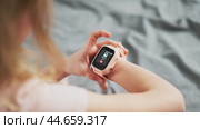 A little girl wears a smartwatch on her wrist and controls the functions by tapping on the screen. Стоковое видео, видеограф Енваев Андрей / Фотобанк Лори